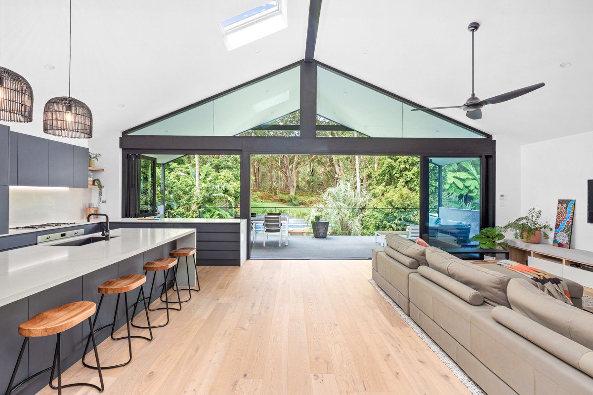 Matte black aluminium framed windows and sliding doors leading onto a balcony in a Northern Beaches home.