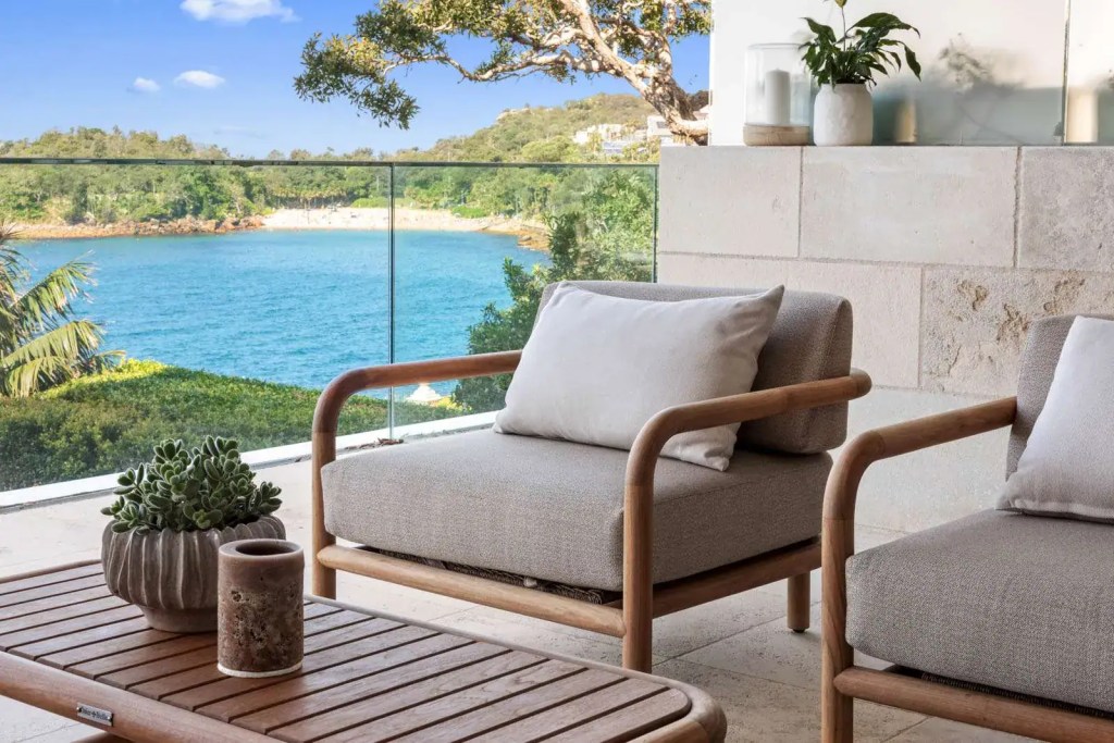 Close‑up of a frameless glass channel‑set balustrade with an interlinking stainless‑steel top rail overlooking the beach from a Manly home