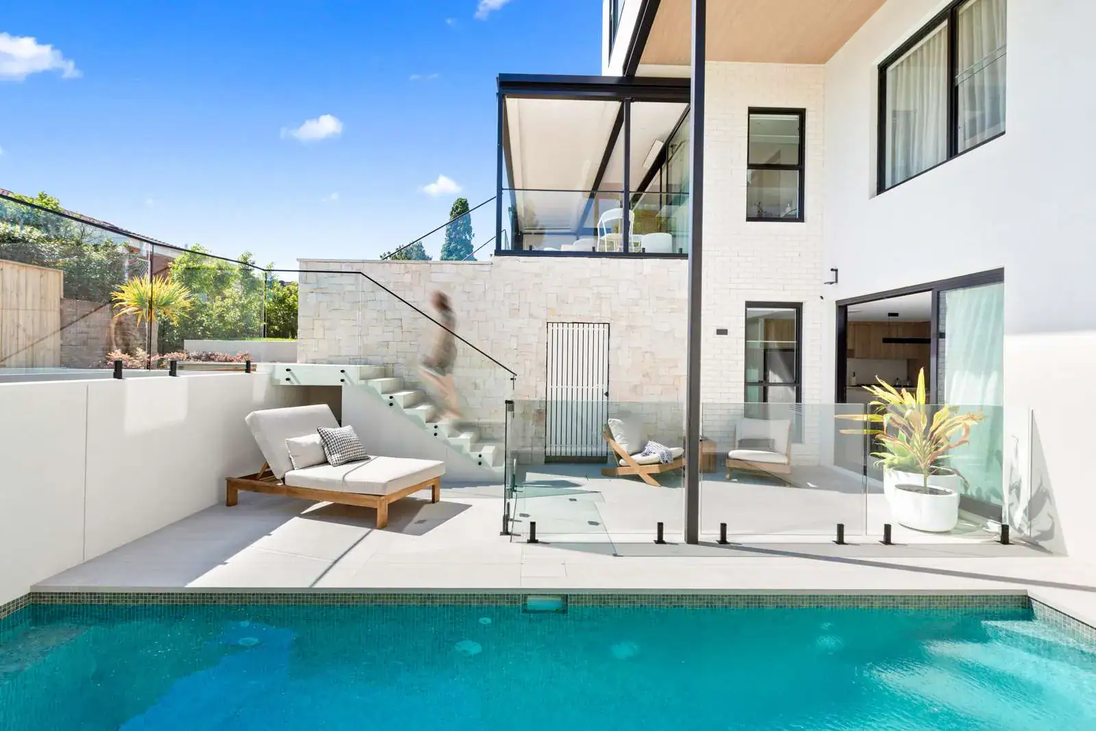 Frameless glass balustrade and pool fence installation by First Class Glass, featuring matte black hardware, in a Northern Beaches home.