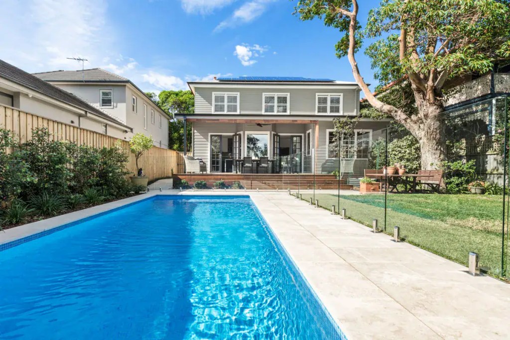 Surface-mounted frameless glass pool fence with polished stainless-steel hardware finish, installed in a Longueville home.