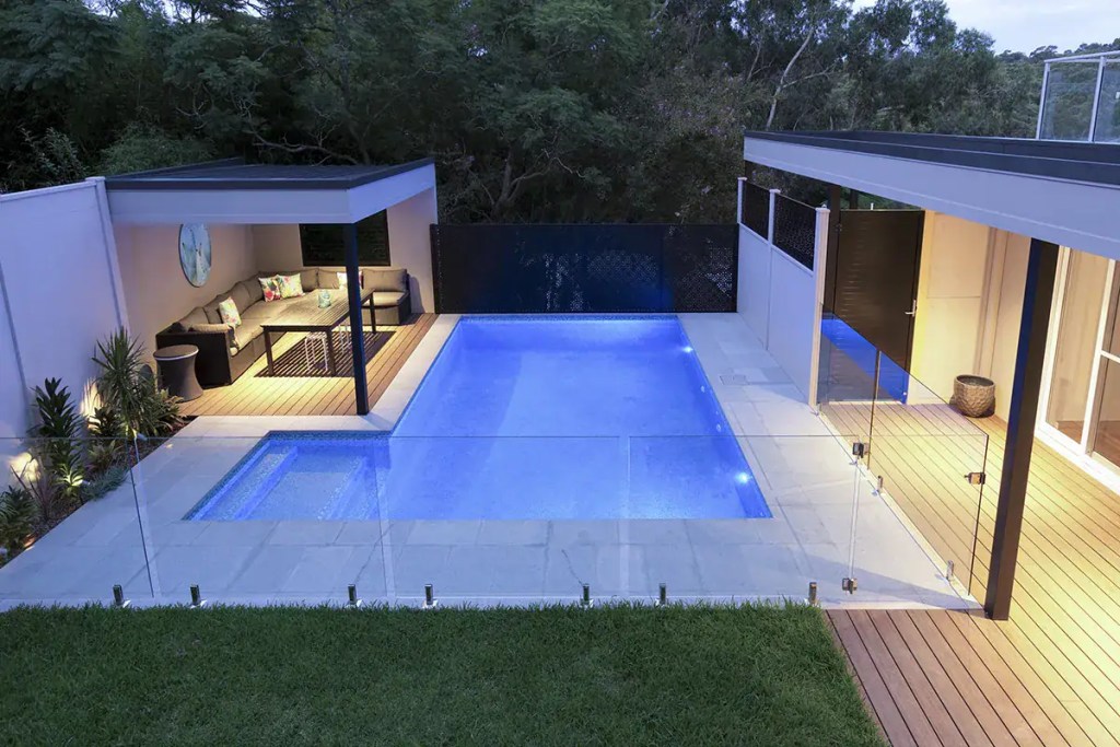Surface-mounted frameless glass pool fence with polished stainless-steel hardware finish, installed in a Northwood home.